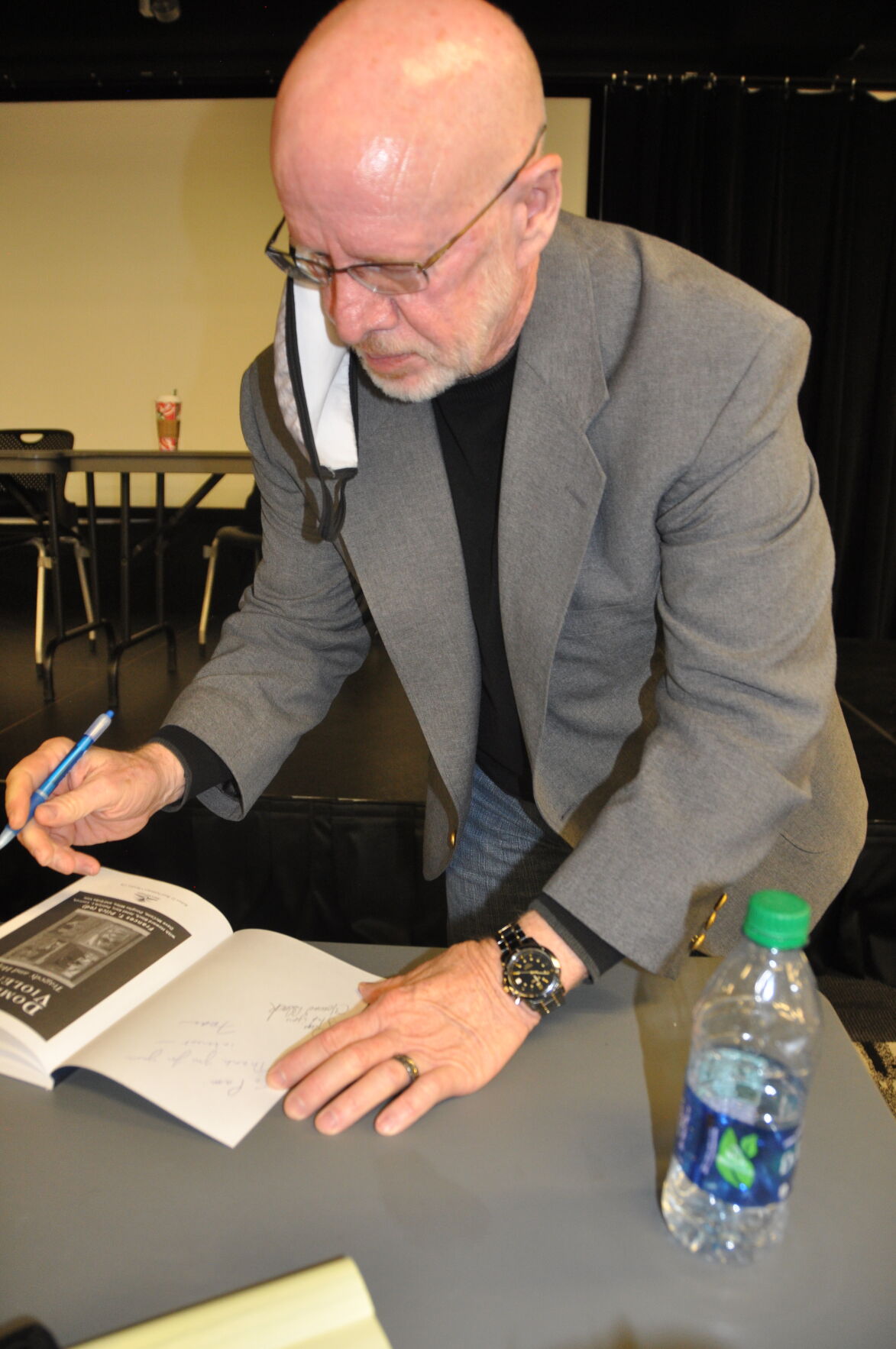 Black signs the book.JPG